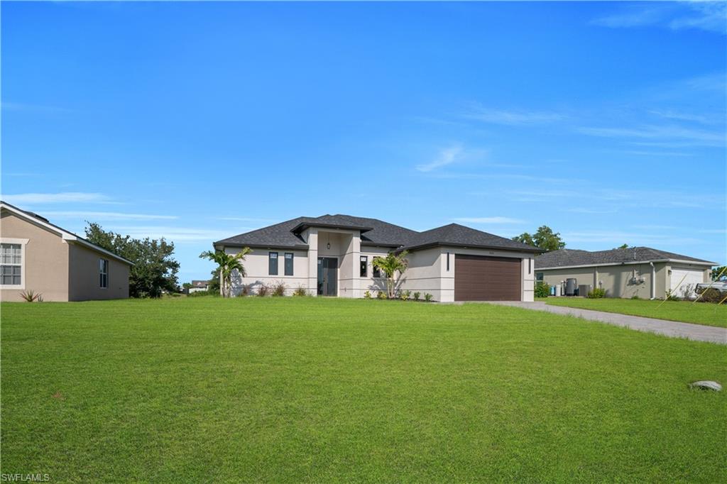 Contemporary stucco exterior with a dark shingle roof, a paver driveway, and an integrated two-car garage