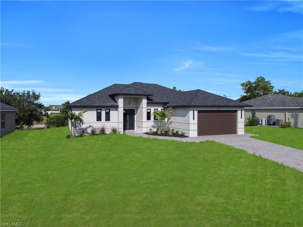 Stucco exterior with a dark shingle roof, paved driveway, and integrated garage
