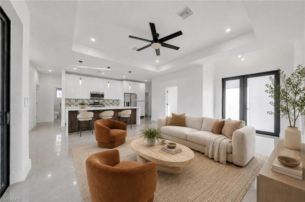 Open-concept living area featuring a tray ceiling, recessed lighting, and a modern ceiling fan