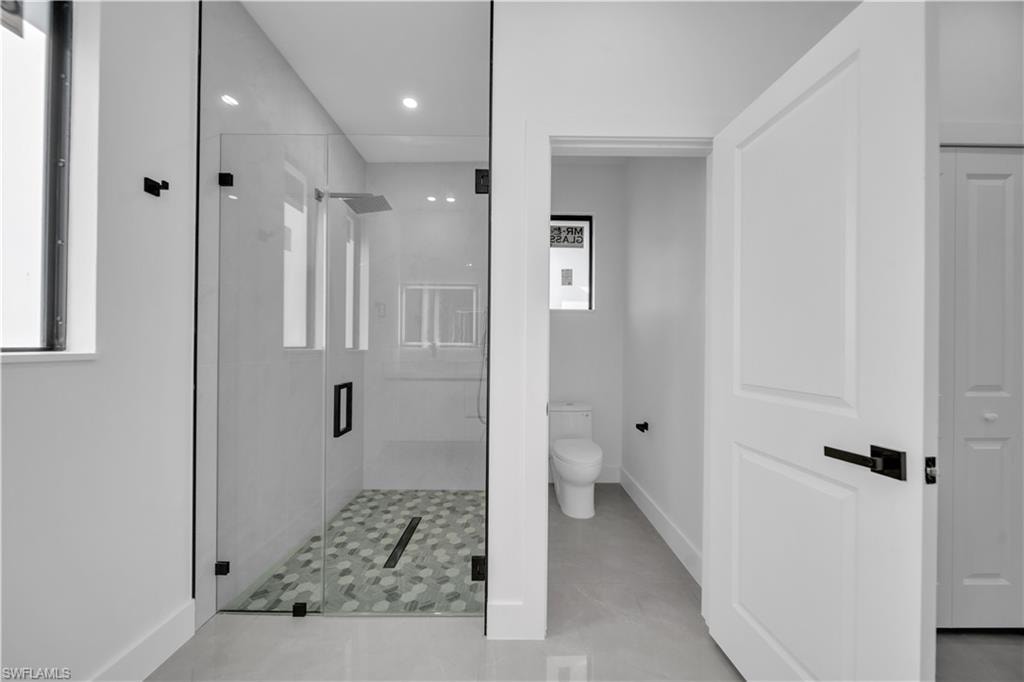 Dual vanity with undermount sinks, contemporary wall-mounted mirrors with backlighting, white flat-panel cabinetry, and two vertical windows