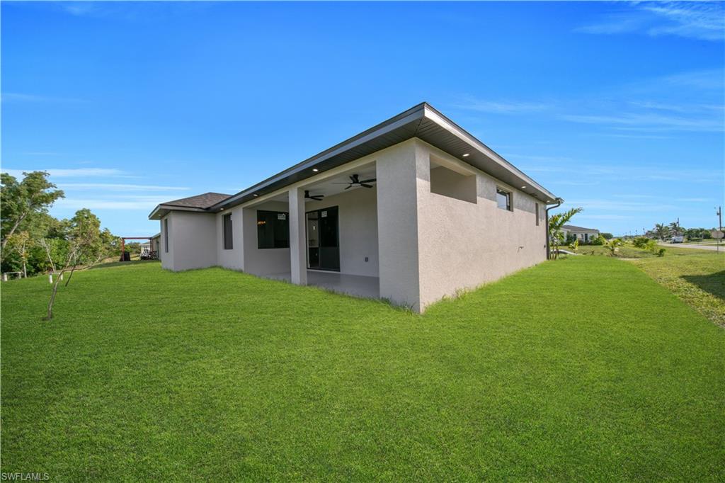 Covered outdoor patio with a tiled floor, two ceiling fans, recessed lighting, and a manicured lawn