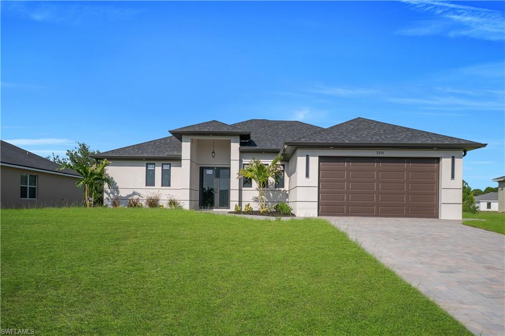Stucco exterior with stone accents, paver driveway, dark-hued garage door, and a shingle roof