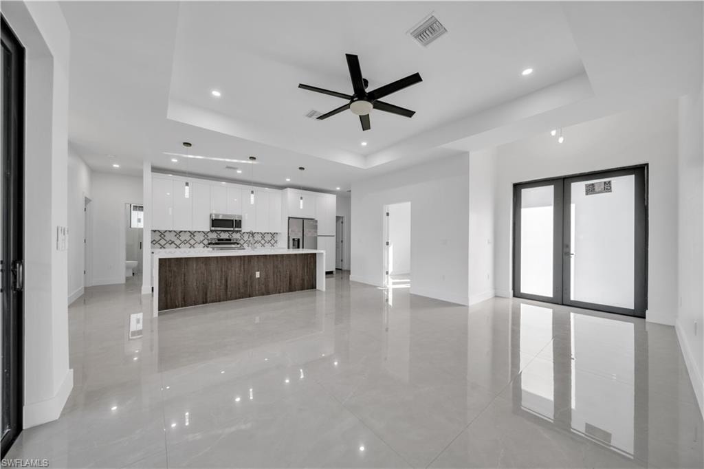 Polished tile flooring throughout, featuring a kitchen with white cabinetry, stainless steel appliances, and a wood-finish island with a light-toned countertop