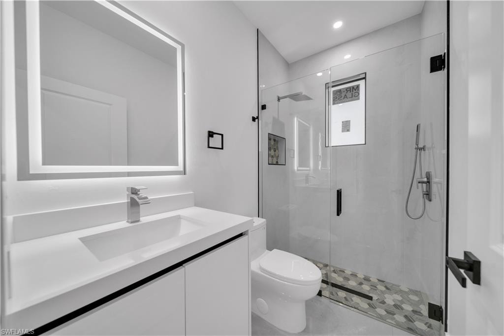 Recessed lighting, ceiling fan with black blades, single window with black trim, light-toned flooring, and white wall finishes
