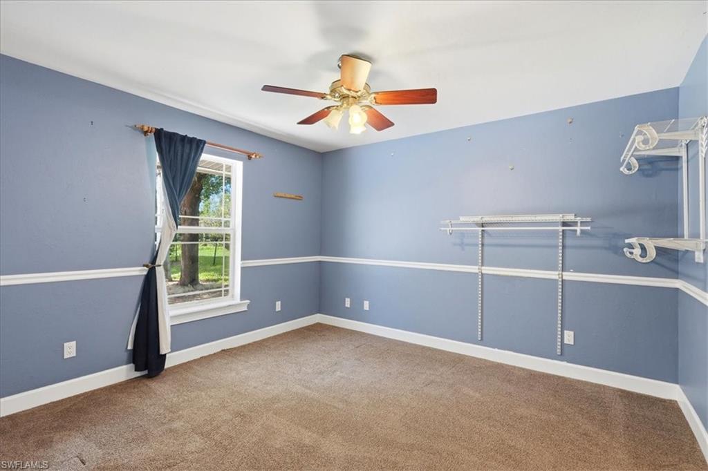 Carpeted flooring, crown molding, built-in shelving, and a ceiling fan with integrated lighting