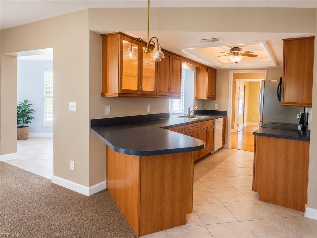 Kitchen featuring wood cabinetry, dark countertops, a built-in dishwasher