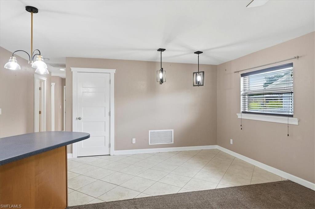 Open concept living area featuring recessed lighting, tile flooring, contemporary pendant lights, and a contrasting carpeted section