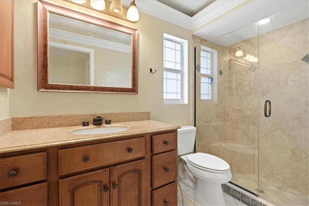 Vanity with a granite-style countertop, undermount sink, and wood-finish cabinetry