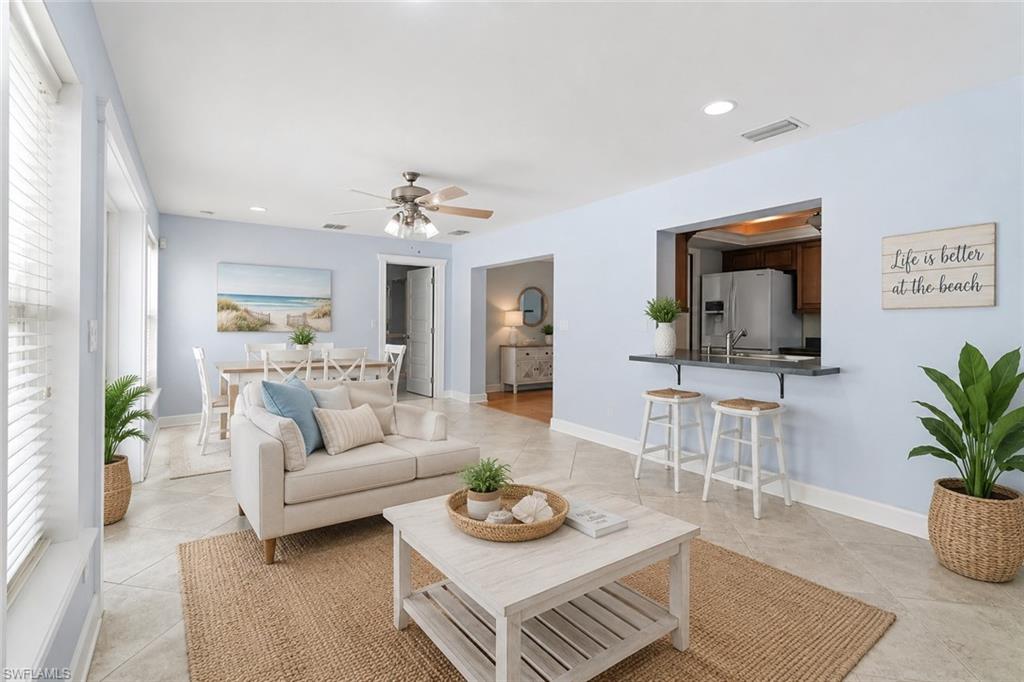 Spacious living area featuring tile flooring, ceiling fan, and abundant natural light from multiple windows