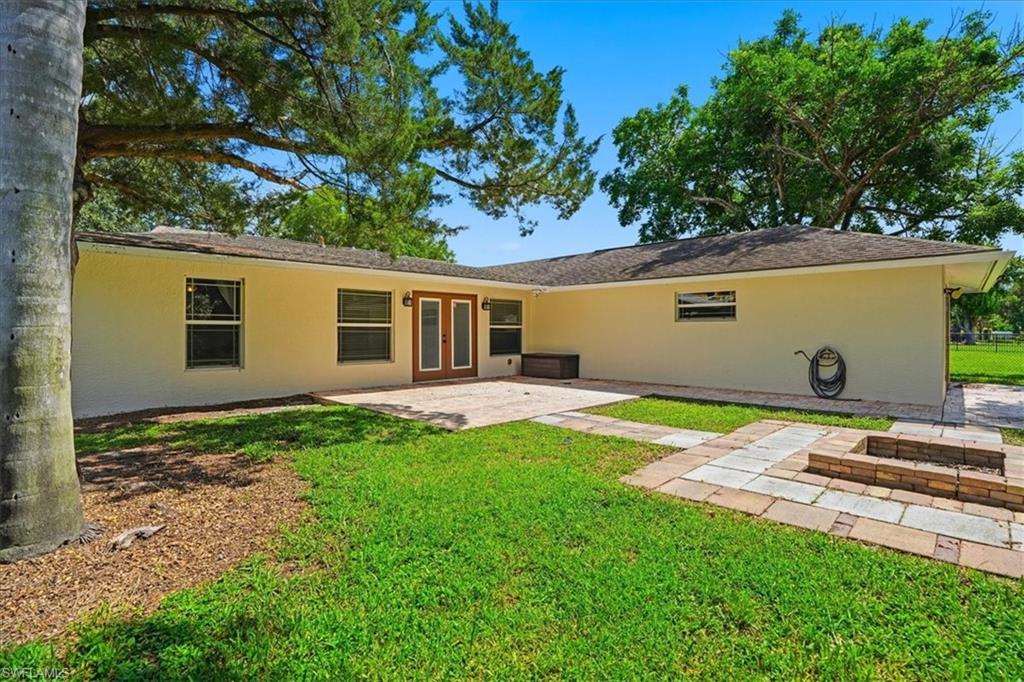 Exterior featuring a stucco finish, wood-frame double doors, paved patio, and a paver-stone fire pit area