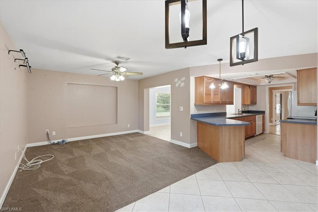 Open-concept living space featuring carpet flooring, ceiling fan, and pendant lighting