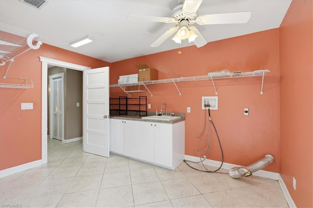 Tiled flooring, built-in cabinetry, utility sink, ceiling fan, and wire shelving