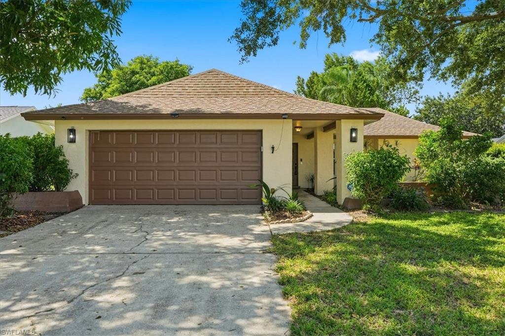 Stucco exterior with a shingle roof, two outdoor wall sconces, and a two-car garage with a panel door