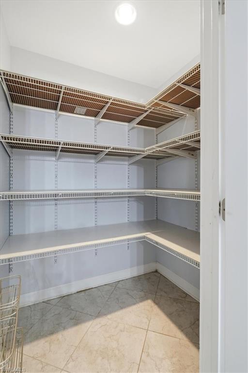 Walk-in pantry featuring wire shelving, tile flooring, and overhead lighting