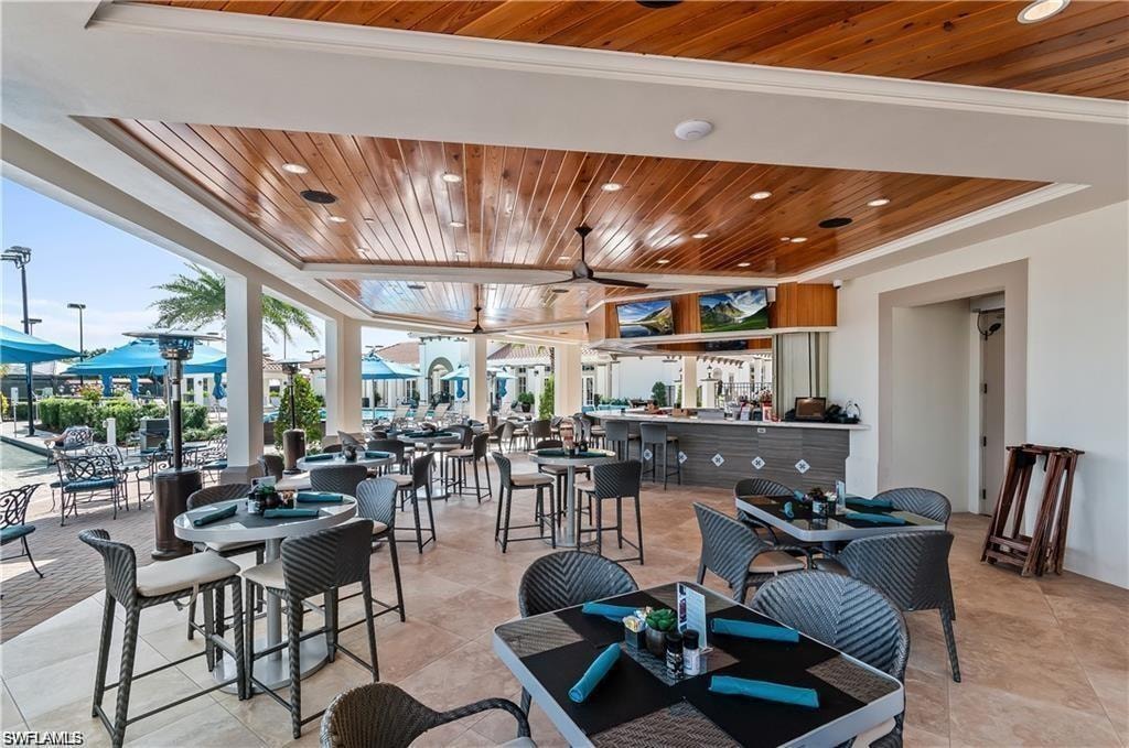Tiled dining space with ornamental molding and wooden ceiling