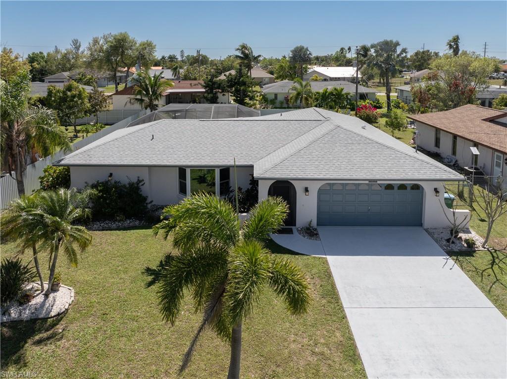 View of front facade with a shingled roof, concrete driveway, an attached garage, a front lawn, and stucco siding