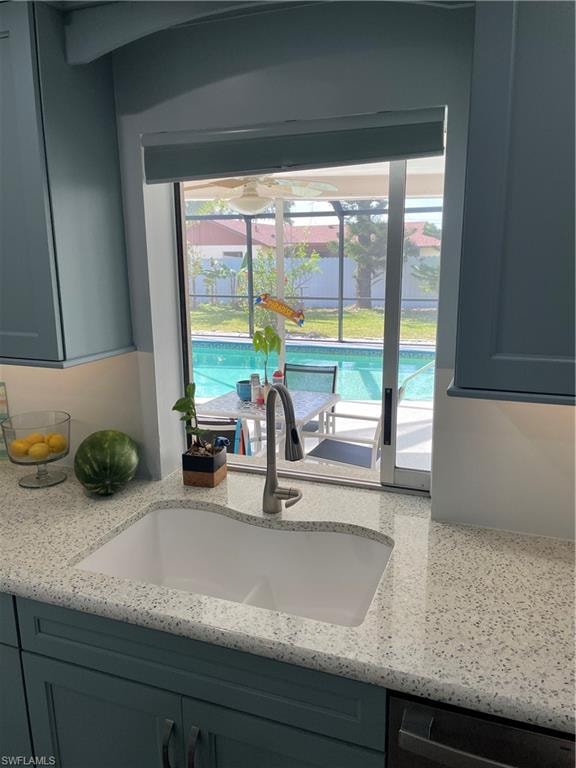 Room details with dishwashing machine, light stone countertops, and a sink