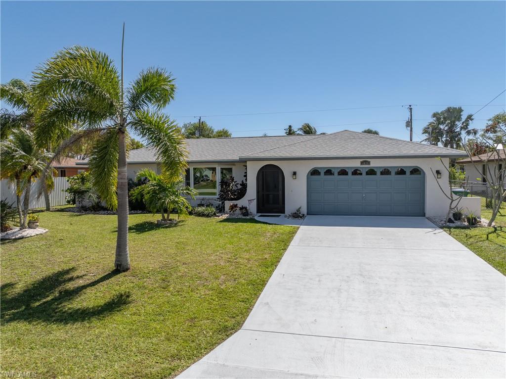 Ranch-style home with a garage, fence, concrete driveway, stucco siding, and a front yard