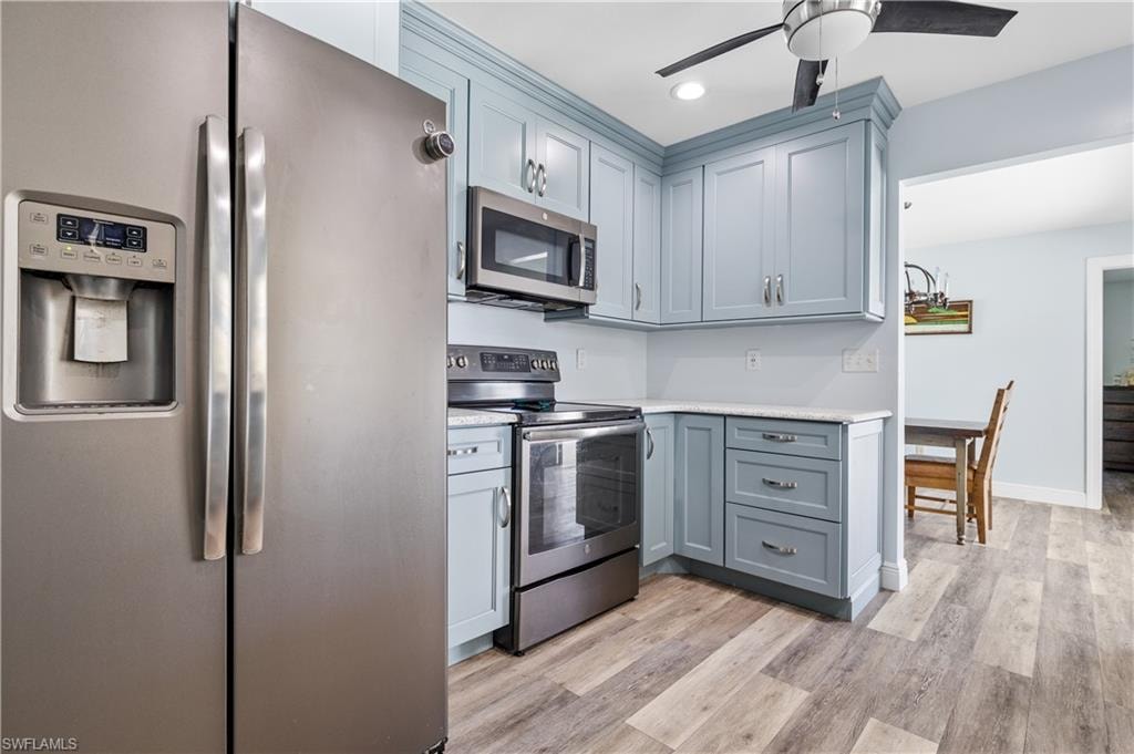 Kitchen with stainless steel appliances, light wood finished floors, gray cabinets, and light countertops