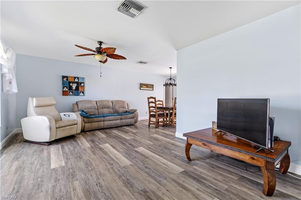 Living area featuring baseboards, visible vents, ceiling fan, and wood finished floors