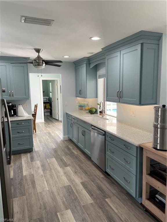 Kitchen with a sink, a ceiling fan, refrigerator, wood finished floors, and dishwashing machine