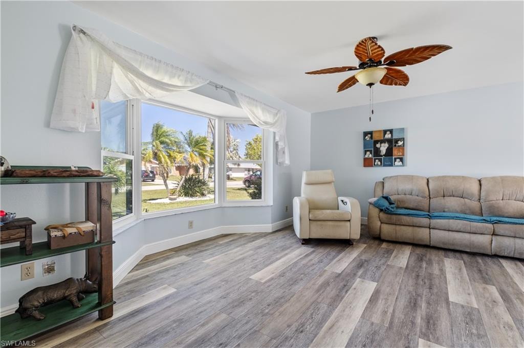 Living area with a ceiling fan, baseboards, and wood finished floors