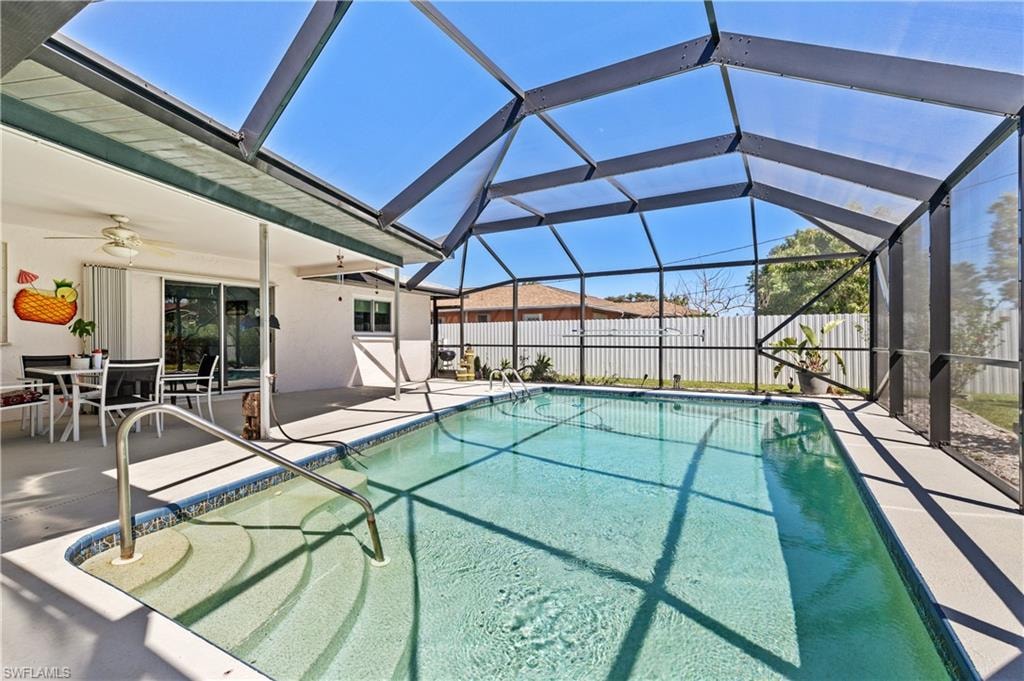 View of swimming pool featuring ceiling fan, glass enclosure, fence, a fenced in pool, and a patio area