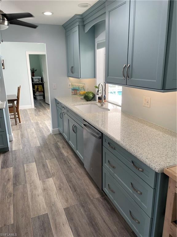 Kitchen with a sink, dark wood-style floors, light stone counters, ceiling fan, and dishwasher