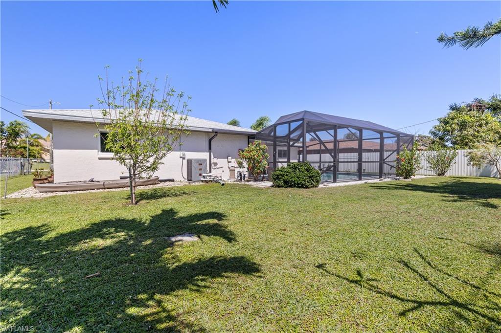 Rear view of house featuring a yard, a fenced backyard, a lanai, and stucco siding