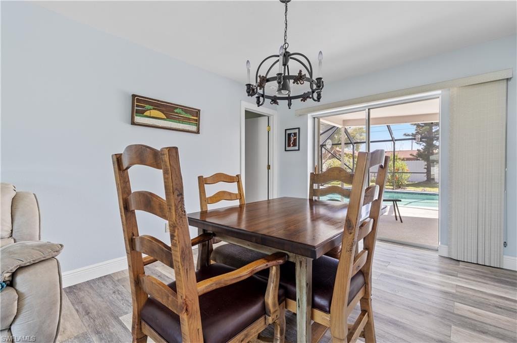 Dining space featuring light wood-style floors, a notable chandelier, and baseboards