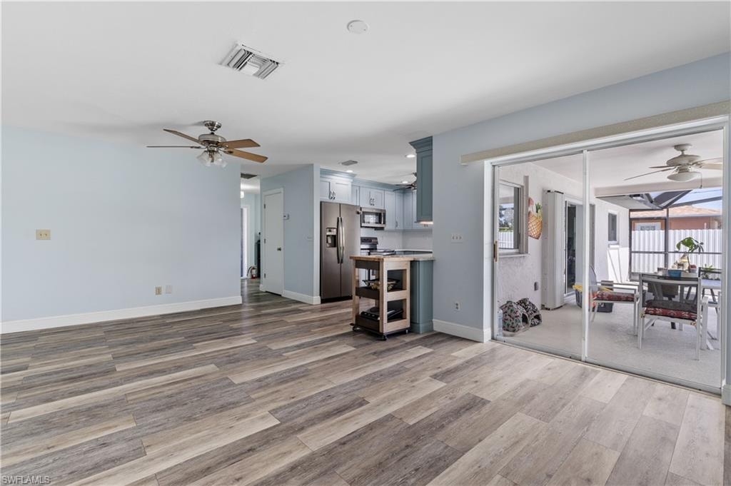 Living room featuring baseboards, wood finished floors, visible vents, and a ceiling fan