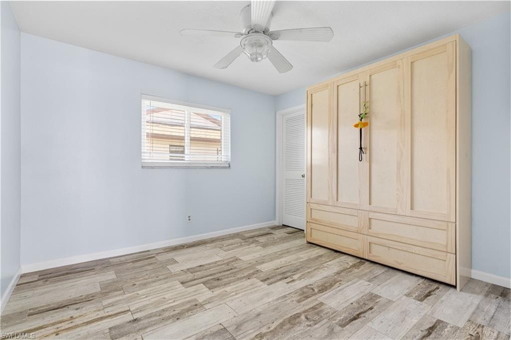 Unfurnished bedroom with ceiling fan, light wood-style flooring, and baseboards