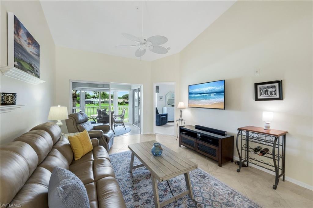 Living area featuring Reclining Couch, Chair, Roomba, light tile patterned flooring, high vaulted ceiling, and a ceiling fan