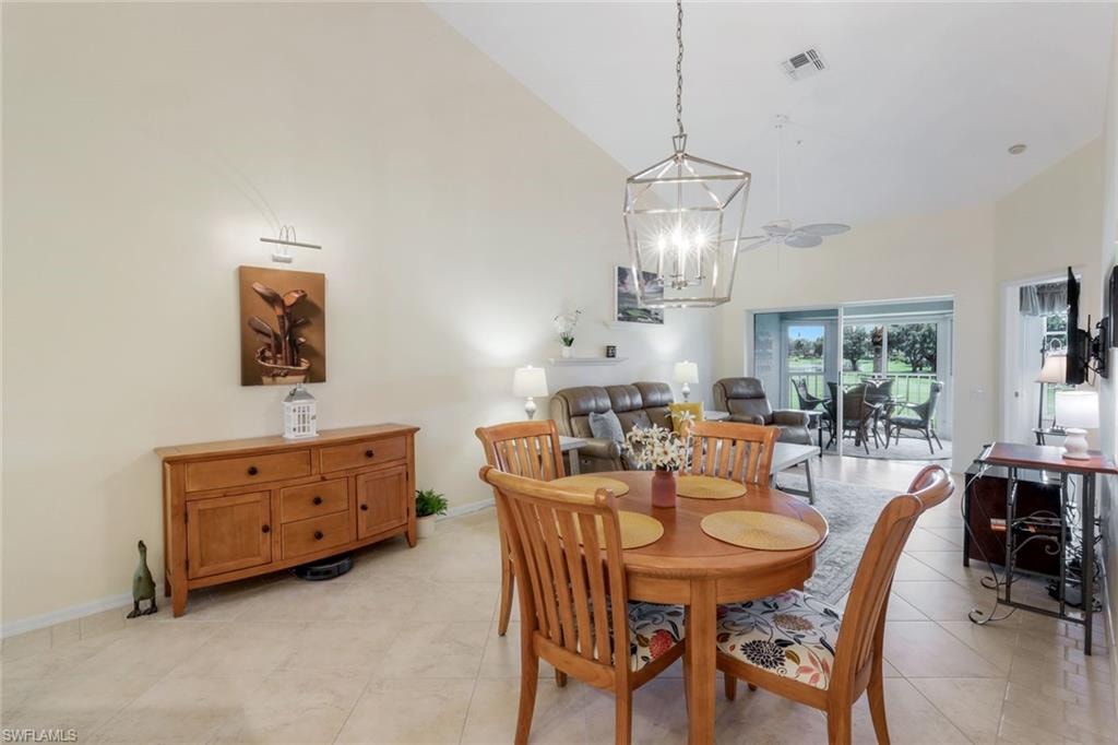 Dining space featuring high vaulted ceiling, light tile patterned floors, and a chandelier