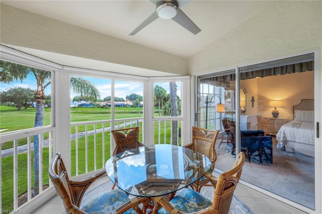 Sunroom with golf course view, lofted ceiling, tile patterned floors, and a textured wall