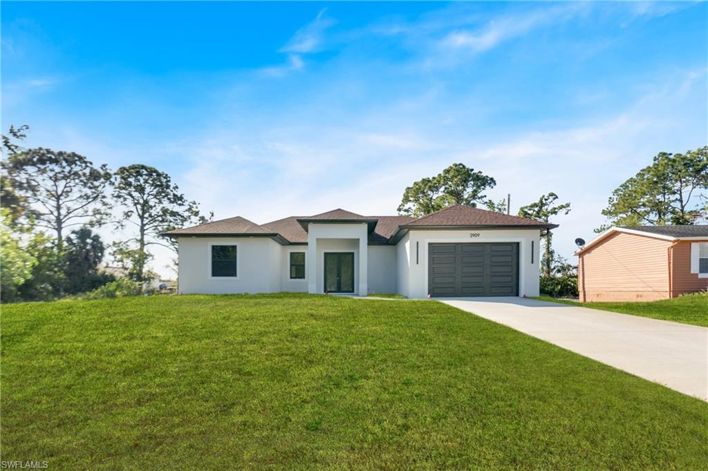 Contemporary stucco exterior with an integrated garage, dark garage door, and a concrete driveway