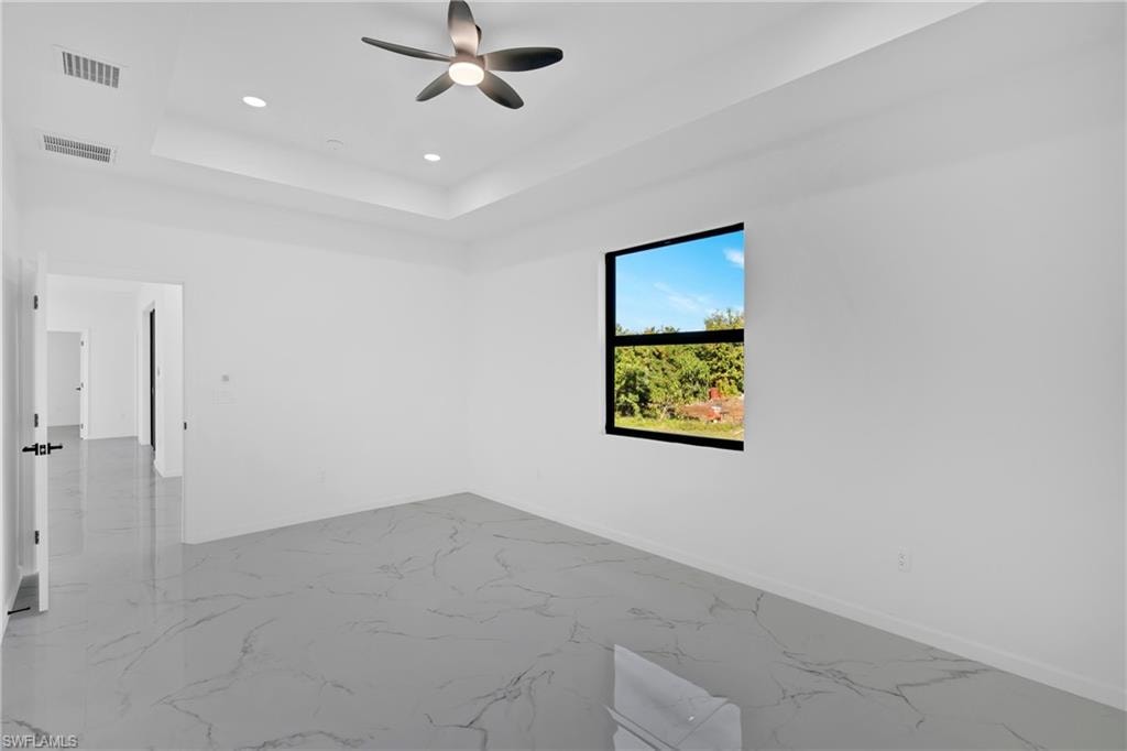 Recessed lighting, tray ceiling, ceiling fan, large window, and polished tile flooring