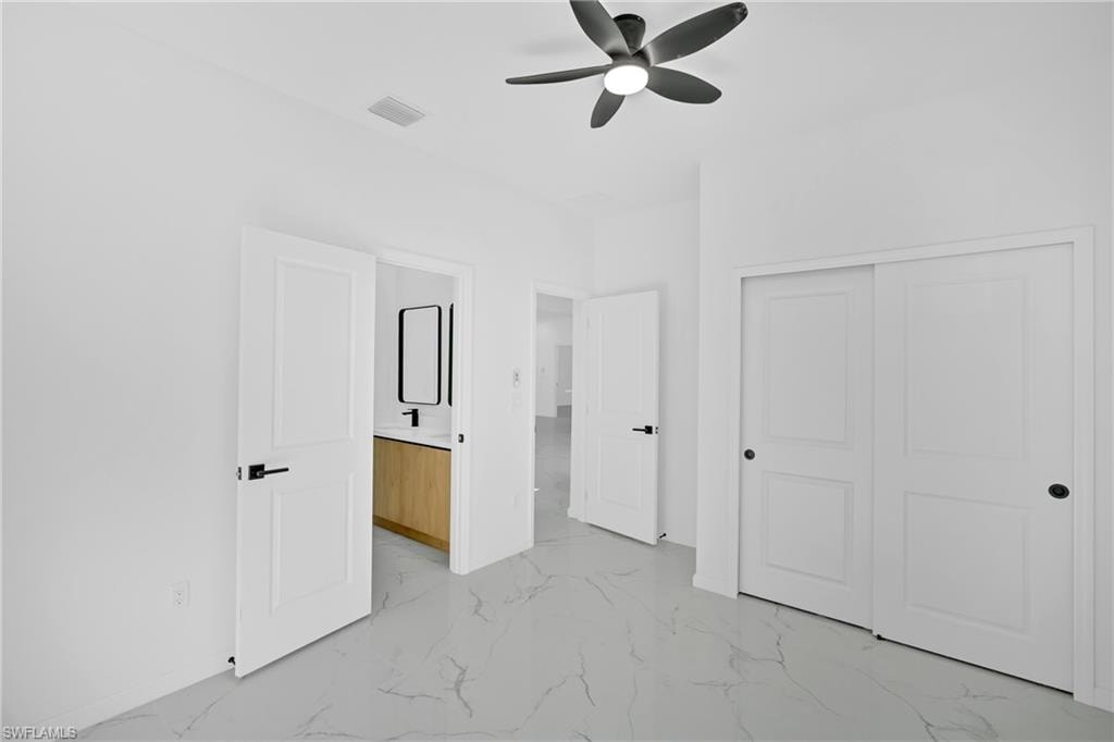 White tile flooring, modern ceiling fan, white paneled doors, black door hardware, light wood-finish vanity