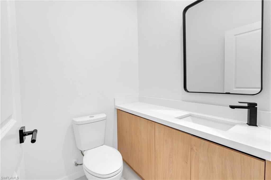 Modern vanity with a light wood-finish base, integrated white sink, and matte black faucet