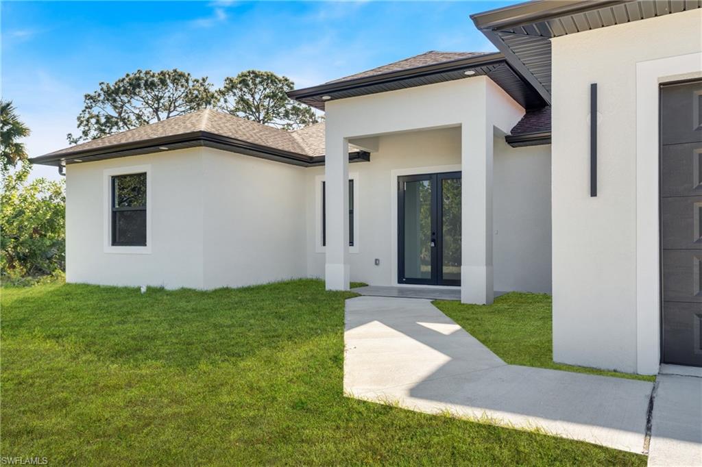 Contemporary exterior with a smooth stucco finish, dark framed windows, a covered entry, and a concrete pathway leading to the double-door entrance