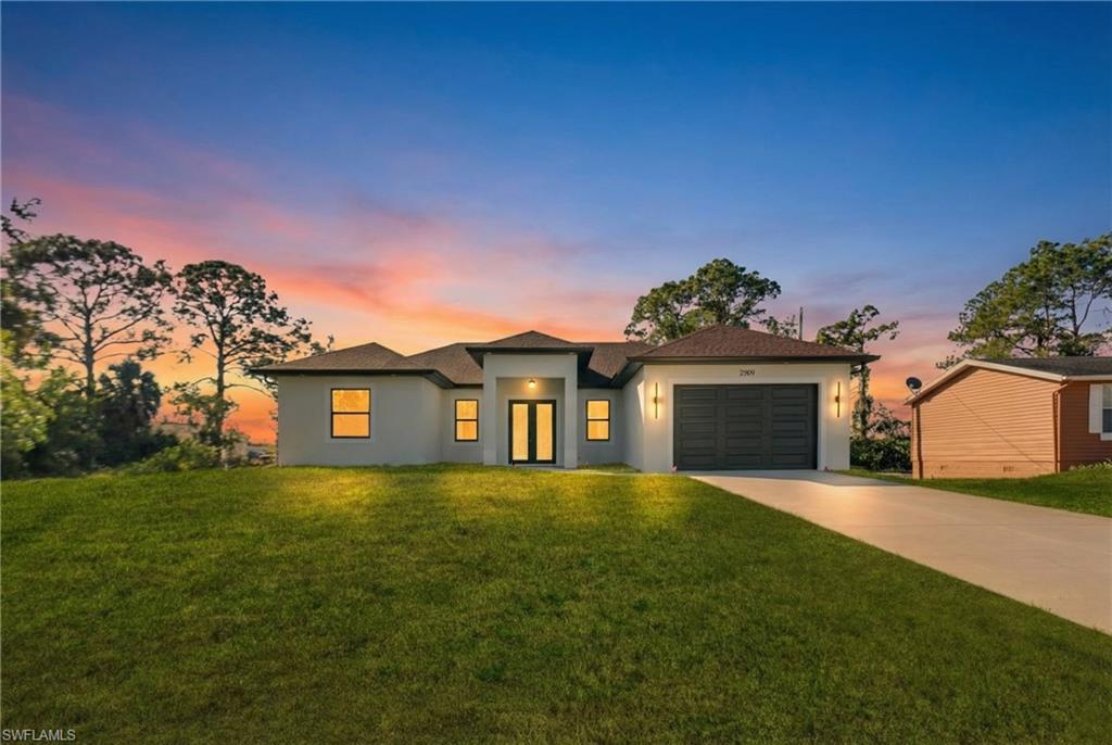 Smooth stucco exterior featuring a dark brown shingle roof, attached garage with panel door, and a paved driveway