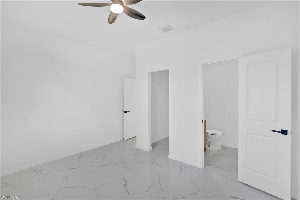 White walls, ceiling fan, white paneled doors, black door hardware, and large format tile flooring