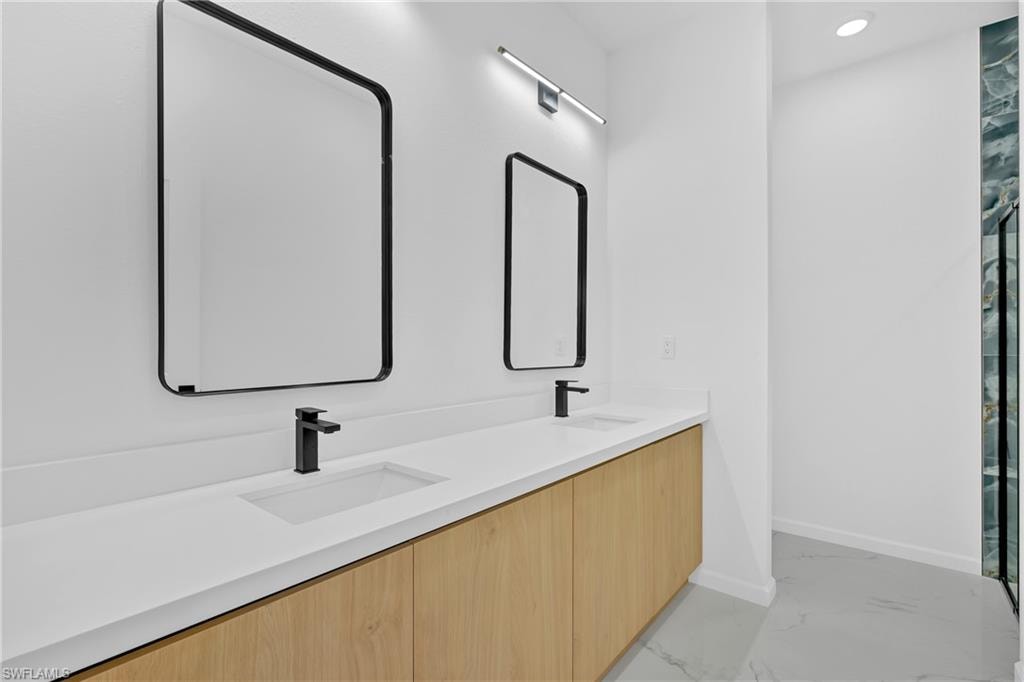 Dual rectangular sinks with matte black single-handle faucets, set into a light-toned countertop