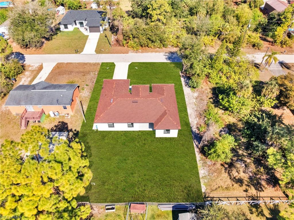 Red tile roof, white exterior, expansive green lawn, and concrete driveway