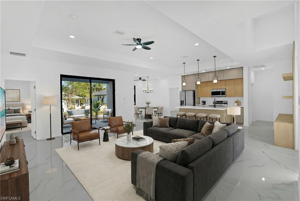 Open-concept living area with white walls, recessed lighting, and large format tile flooring
