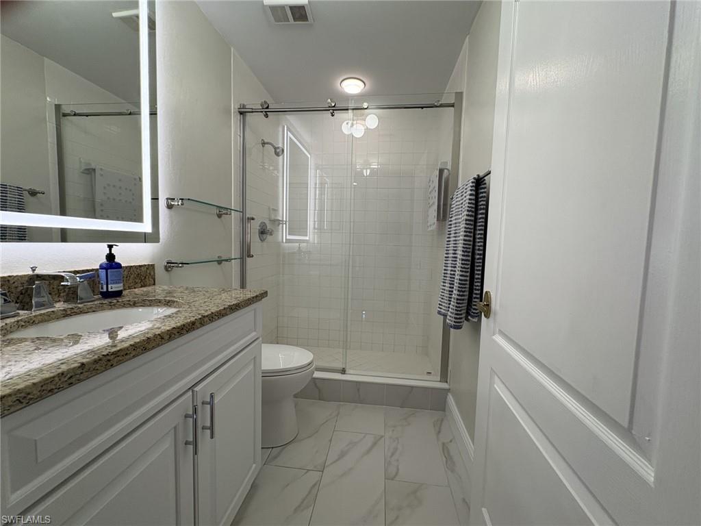 Full bath with vanity, marble look tile flooring, and a stall shower