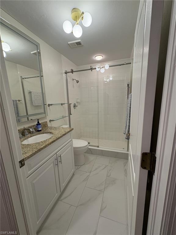 Full bathroom featuring vanity, marble finish flooring, and a shower stall
