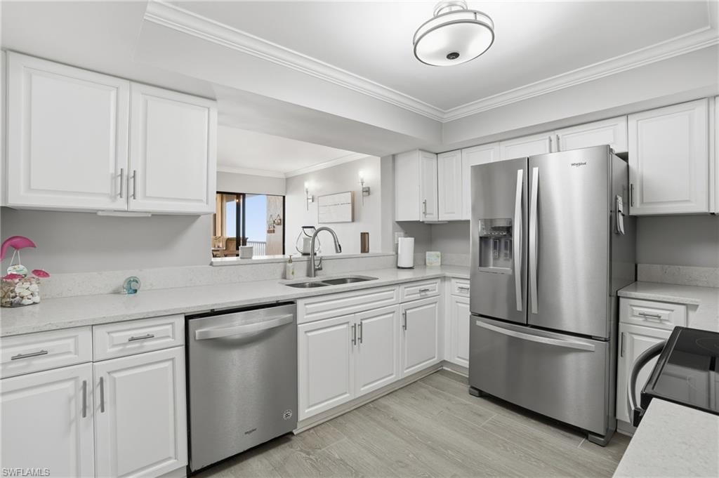 Kitchen with stainless steel appliances, white cabinetry, and crown molding