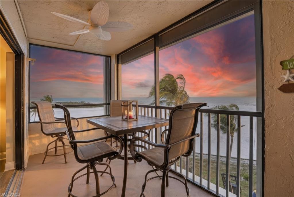 Sunroom / solarium with a water view, a textured wall, expansive windows, and a textured ceiling