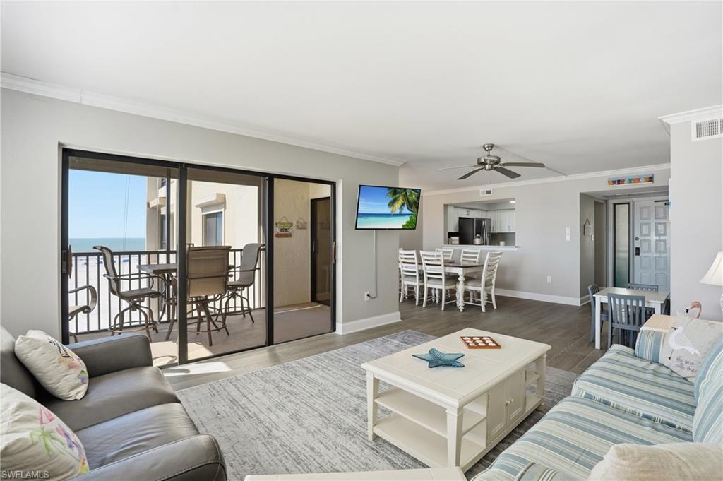 Living room with crown molding, wood finished floors, and a ceiling fan